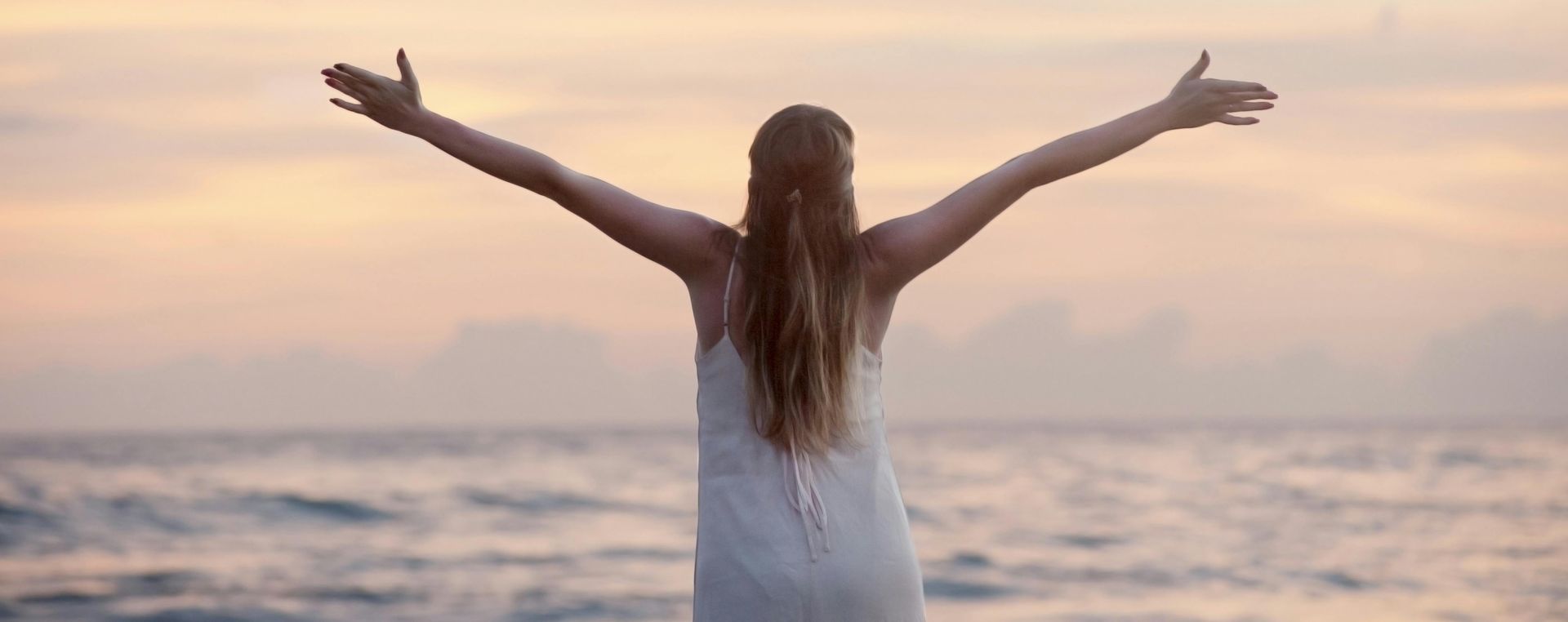 A woman enjoying a serene sunset on Unawatuna Beach, Sri Lanka, depicting peace and freedom.