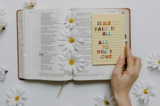 An open Bible adorned with white daisies and a faith-based note, creating a serene and inspiring setting.