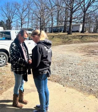 A thoughtful woman with afro hair in a gray blazer poses indoors, conveying a sense of introspection.